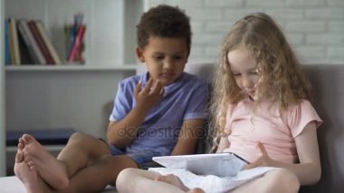 Rahat koltukta oturan ve tablet çizgi film izlerken çok ırklı çocuklar