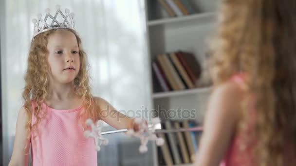 Маленька дівчинка дивиться на дзеркальне відображення, одягнена у вишукану сукню принцеси, магія — стокове відео