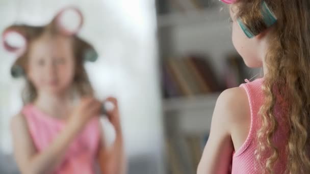 Ragazza carina gonfiore e facendo i capelli davanti allo specchio proprio come sua madre — Video Stock