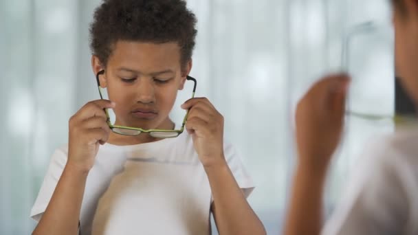 Upprörd Afro-American kid att sätta glasögon på och av, syn problem, hälso-och sjukvård — Stockvideo