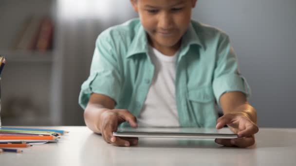 Niño jugando activamente en la tableta después de la escuela, adicción a los juegos en línea — Vídeo de stock