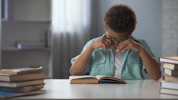 Liten pojke gnugga trött från aktiv läsning ögon, göra massor av läxor — Stockvideo
