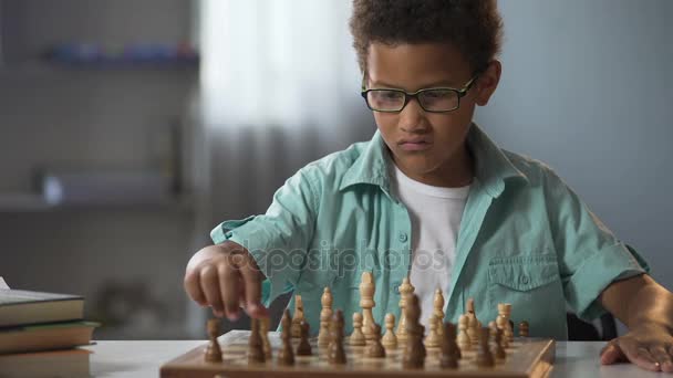 Mądry chłopak gra w szachy starannie myślenia przez każdego ruchu, gra logiczna — Wideo stockowe