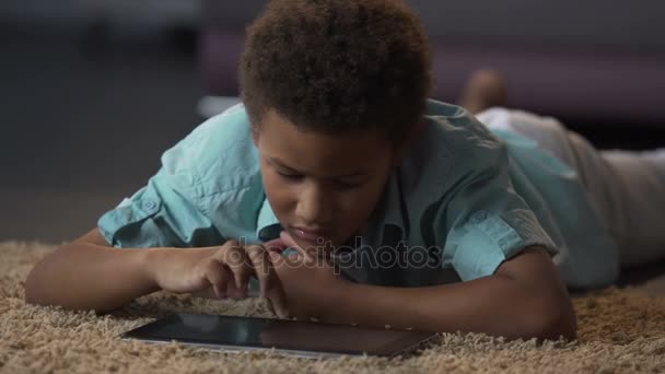 Niño viendo vídeo en la tableta, aburrido en casa, ocio mal organizado para el niño — Vídeos de Stock