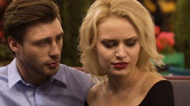 Kızgın sarışın kadın oturma sonraki kocası, özür diler gibi dokunmaya çalışan adam