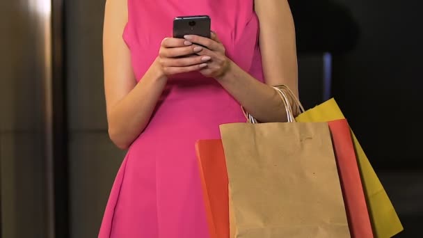 Female holding bags and using mobile phone, application for discounts, shopping — Stock Video