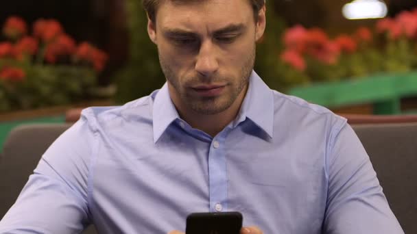 Businessman sitting in restaurant and looking at mobile phone, checking mail — Stock Video