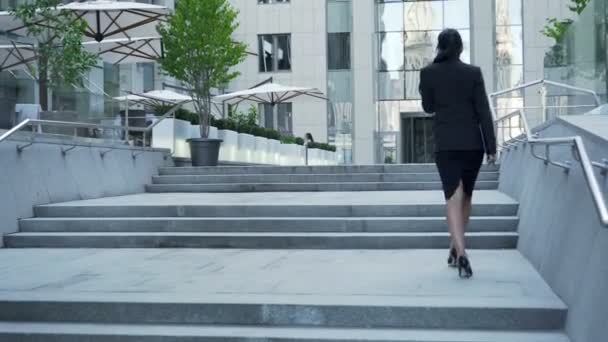 Femme d'affaires marchant dans les escaliers jusqu'à l'immeuble, vue de derrière, échelle de carrière — Video