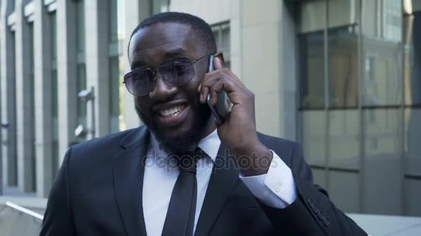 Afroamericano en traje de negocios hablando por celular, sonrisa radiante, éxito — Vídeo de stock