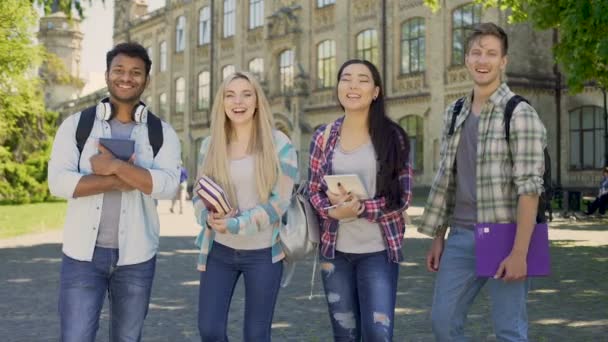 Estudantes de raça mista rindo olhando para a câmera, de pé no campus universitário — Vídeo de Stock