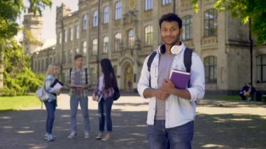 Mükemmel öğrenci onun üniversite duran içtenlikle kameraya gülümseyen