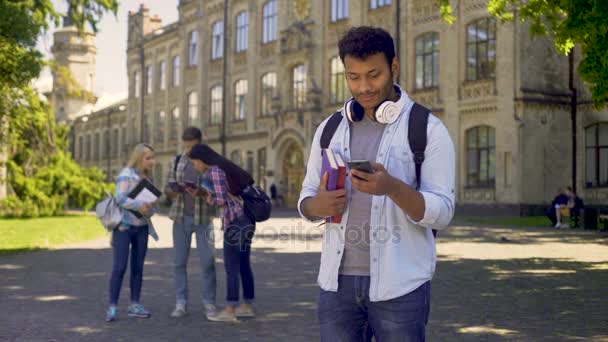 Alegre estudiante masculino usando la aplicación móvil en el teléfono inteligente, buscando trabajo en línea — Vídeo de stock