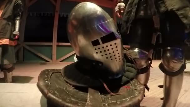 Homem de armadura de cavaleiro em pé junto ao banco com capacete, reencenação de eventos — Vídeo de Stock