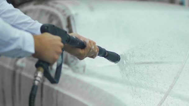 Руки чоловіка, що тримає розпилювач, покривають дорогу авто піною, миття автомобілів — стокове відео