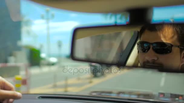 Reflejo de cara masculina en gafas de sol en espejo retrovisor en coche en movimiento, tráfico — Vídeo de stock