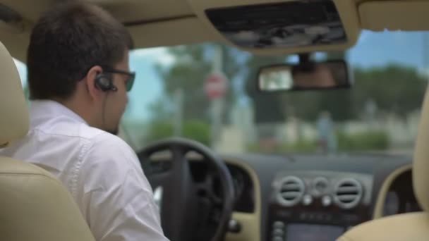 Joven hombre sentado en el asiento de los conductores de automóviles caros, mostrando pulgares hacia arriba, prueba de conducción — Vídeo de stock