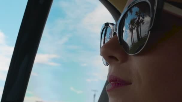 Mujer montando en el asiento trasero del coche, reflejo de las palmas y frente al mar en gafas de sol — Vídeos de Stock