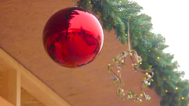Reflejo de los transeúntes en brillante bola de Navidad colgando bajo el techo de la casa — Vídeos de Stock