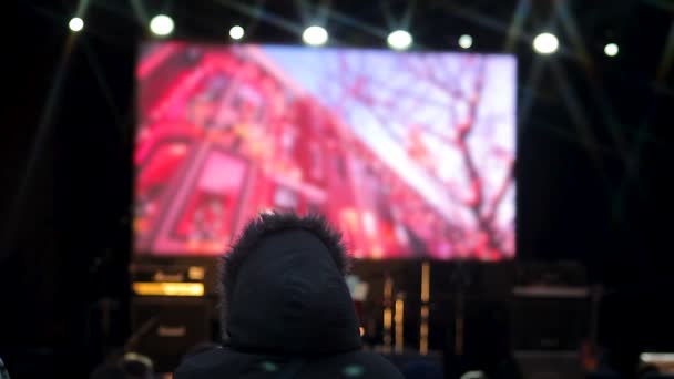 La gente viendo clips de la próxima celebración en la pantalla grande en la plaza central — Vídeos de Stock