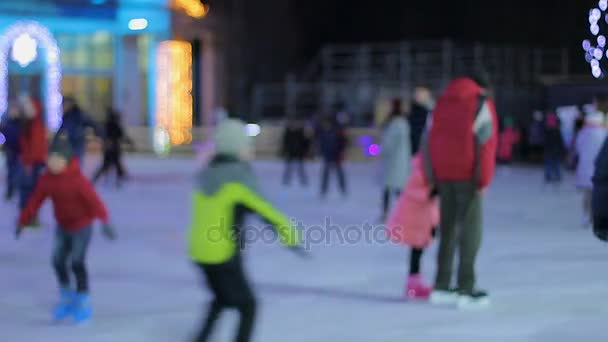 Jóvenes alegres y familias patinando en pista de hielo, recreación activa — Vídeo de stock