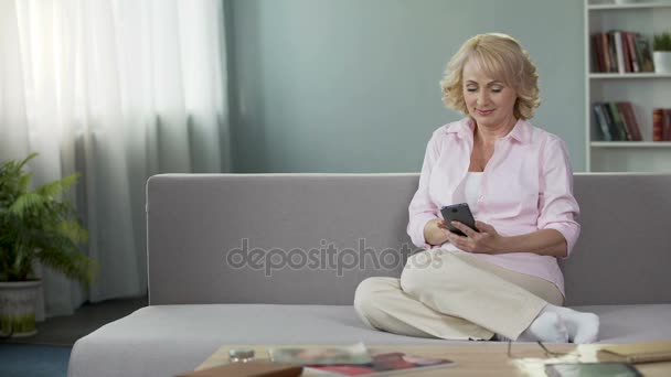 Preciosa mujer de mediana edad viendo fotos en las redes sociales en el teléfono celular, aplicación — Vídeos de Stock
