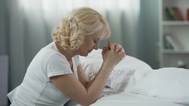 Fürsorgliche Mutter sitzt am Bett und betet für Kinder, Hoffnung und Religion — Stockvideo