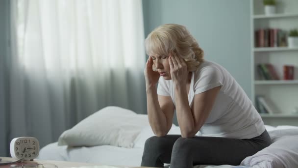 Seniorin sitzt auf Bett und leidet unter schrecklichen Kopfschmerzen, Gesundheitsproblem — Stockvideo