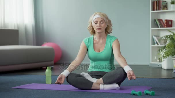 Reife Dame praktiziert Yoga zu Hause, macht Entspannungsübungen, Meditation — Stockvideo
