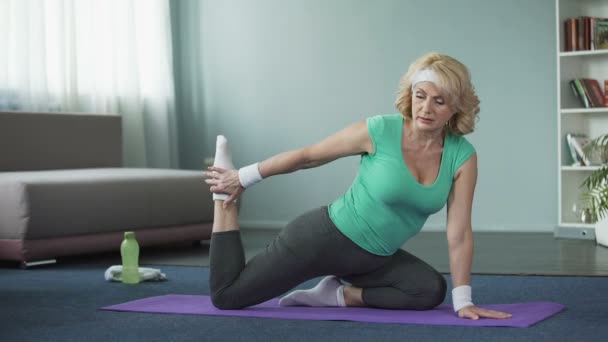 Trött mogen kvinna gör yogaövningar, stretching benen. Hälsosam livsstil — Stockvideo