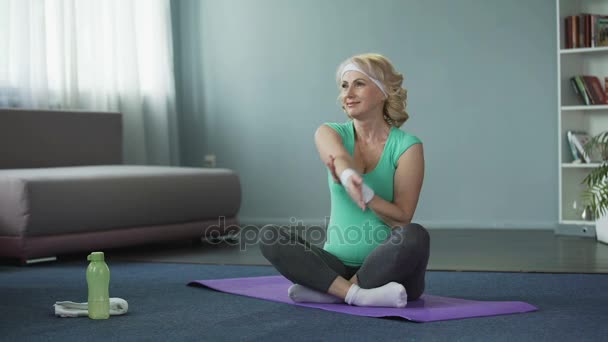 Friska mogna kvinna gör fitnessövningar på yogamatta, träning hemma — Stockvideo