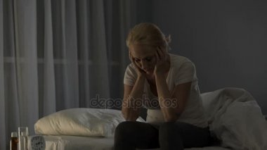 Yatakta, şiddetli migren ve kötü ağrı nedeniyle uykuya yapamaz oturan Bayan