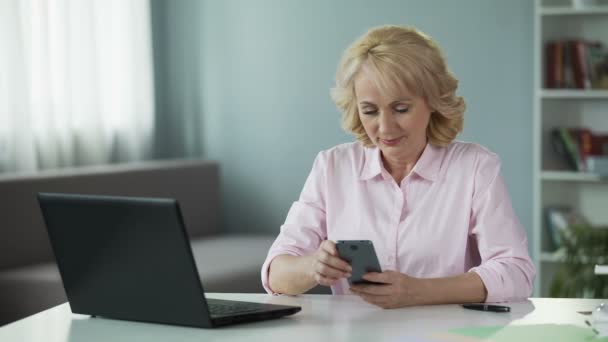 Señora madura viendo las fotos de vacaciones de los niños en el teléfono inteligente, utilizando gadget — Vídeos de Stock