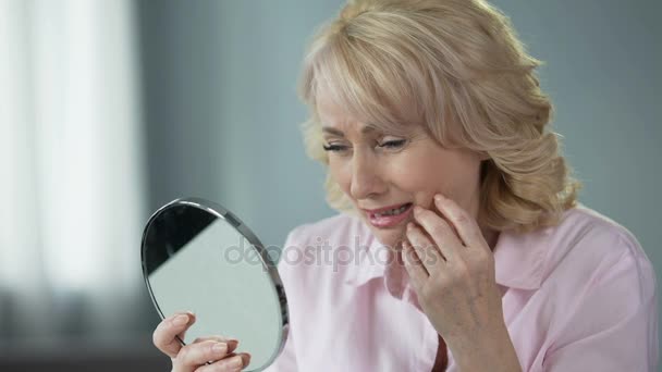 Senhora em seu 50 olhando no espelho lembrando a pele jovem e saudável, nostalgia — Vídeo de Stock