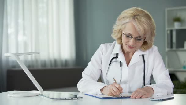 Lady médico preenchendo formulário de seguro de saúde antes de prosseguir para tratar o paciente — Vídeo de Stock