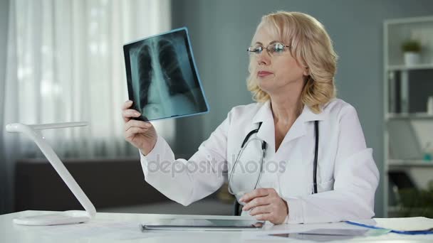 Medico che esamina i raggi X dei polmoni del paziente che prende appunti nelle cartelle cliniche — Video Stock
