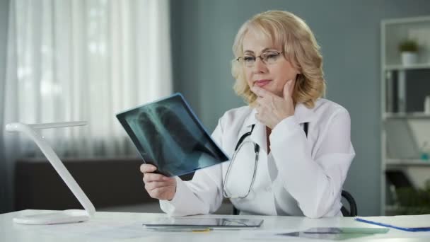 Опытная женщина-рентгенолог изучает рентгеновские снимки, квалифицированную диагностику — стоковое видео