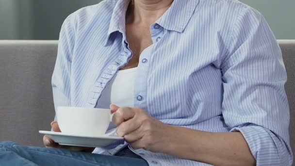 Señora mayor sentada en el sofá, tomando una taza de té disfrutando del olor, relajarse en casa — Vídeo de stock