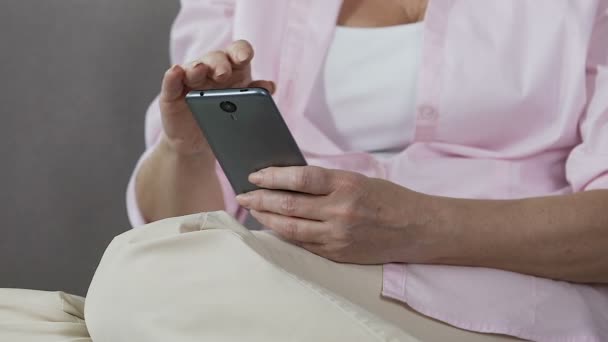 Συνταξιούχος γυναίκα κρατώντας smartphone κύλιση της οθόνης, εύκολη κινητές εφαρμογές — Αρχείο Βίντεο