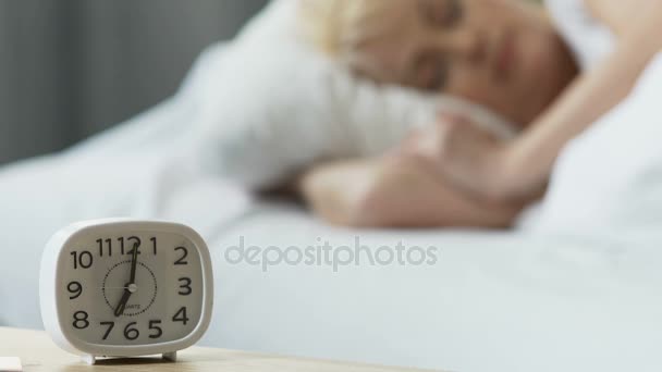 Reloj despertador de pie en la mesita de noche, mujer durmiendo en la cama, comodidad en casa — Vídeos de Stock