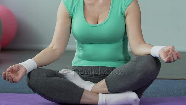 Starší žena sedící na jógu zkříženýma nohama, tělesné pohody, vnitřní rovnováhu