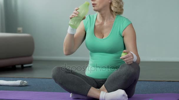 Female of senior age sitting on fitness mat, drinking water, physical activity — Stock Video