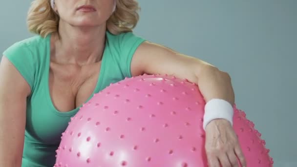 Mulher de meia-idade cansada sonolenta deitada na bola de fitness após o treino ativo — Vídeo de Stock