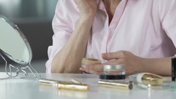 Las manos de la mujer mayor poniendo fundación anti-edad en la cara, cosmetología, primer plano — Vídeos de Stock