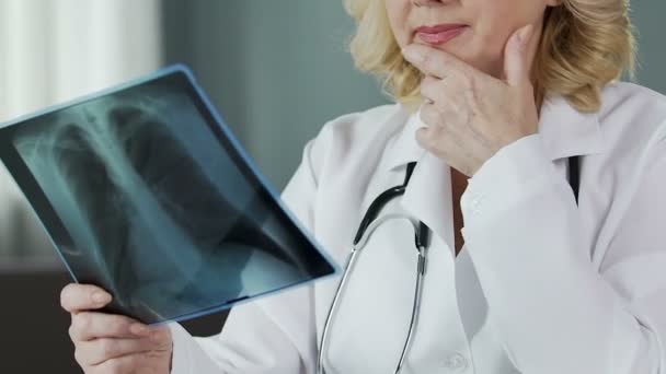 Professionell terapeut tittar på lungröntgen och ler in i kameran, närbild — Stockvideo