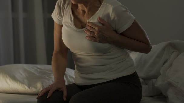 Crise cardiaque, femme âgée assise sur un canapé et touchant la poitrine, problème de santé — Video