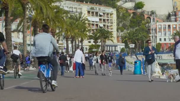 Nice, Frankrijk - omstreeks juni 2016. Toeristen in de stad. Tieners rijden fietsen langs de dijk voorzichtig cirkelen voorbijgangers — Stockvideo