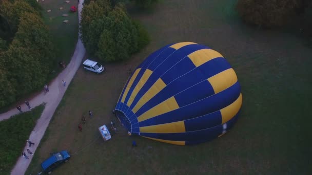 Menschen aufblasen ausgebreitete Heißluftballonhülle auf dem Boden und bereiten Flug vor — Stockvideo