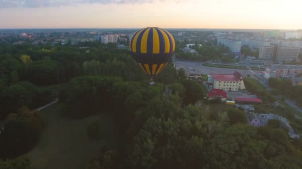 Hete luchtballon zwevend over groen stadsgebied in de ochtend, ontsnapping uit de routine — Stockvideo