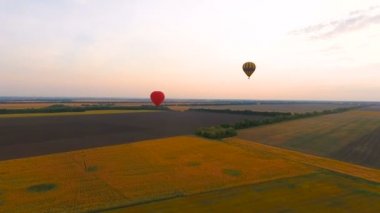 Sıcak hava balonları hava gün batımında parlayan gökyüzüne karşı kırsal alanlar üzerinde yüzen
