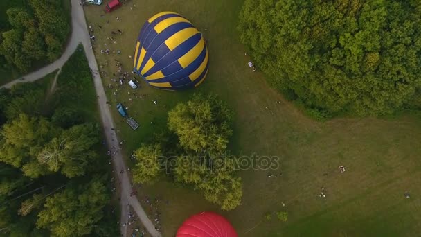 Flera air ballonger liggande på marken och får uppblåst omgiven av publiken — Stockvideo